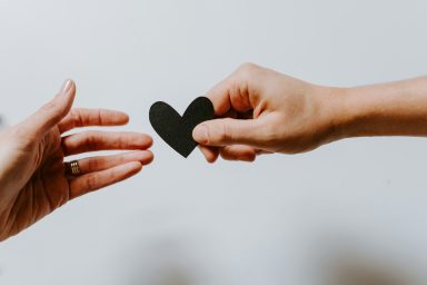 Relations & Consentement Relations et consentement : deux mains qui se transmettent un cœur en papier noir